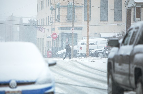 A pedestrian walks in heavy snowfall on Friday, Feb. 16, 2024, in St. Louis' Hill neighborhood.