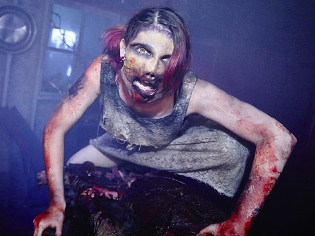 An actor from The Darkness stares at the camera covered in makeup and fake blood.