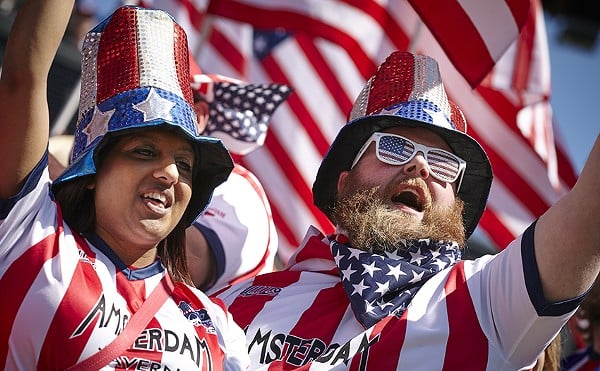 Two fans cheer decked in red-and-wide America-styled hats, sunglasses and t-shirts.
