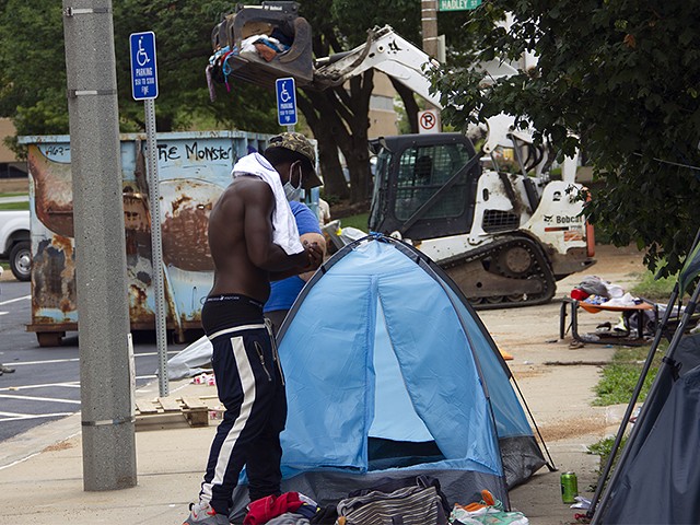 An unhoused resident of Interco Plaza gathers the contents of his tent as city workers clear the encampment.