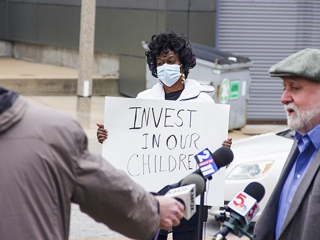 Gwendolyn Cogshell holds a sign urging school officials to "Invest in our children" during a teacher's union press conference opposing school closings on December 15.