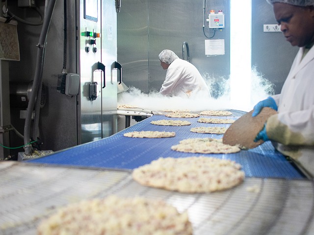 The pizzas being sent through a machine that instantly freezes them and prepares them for packaging.