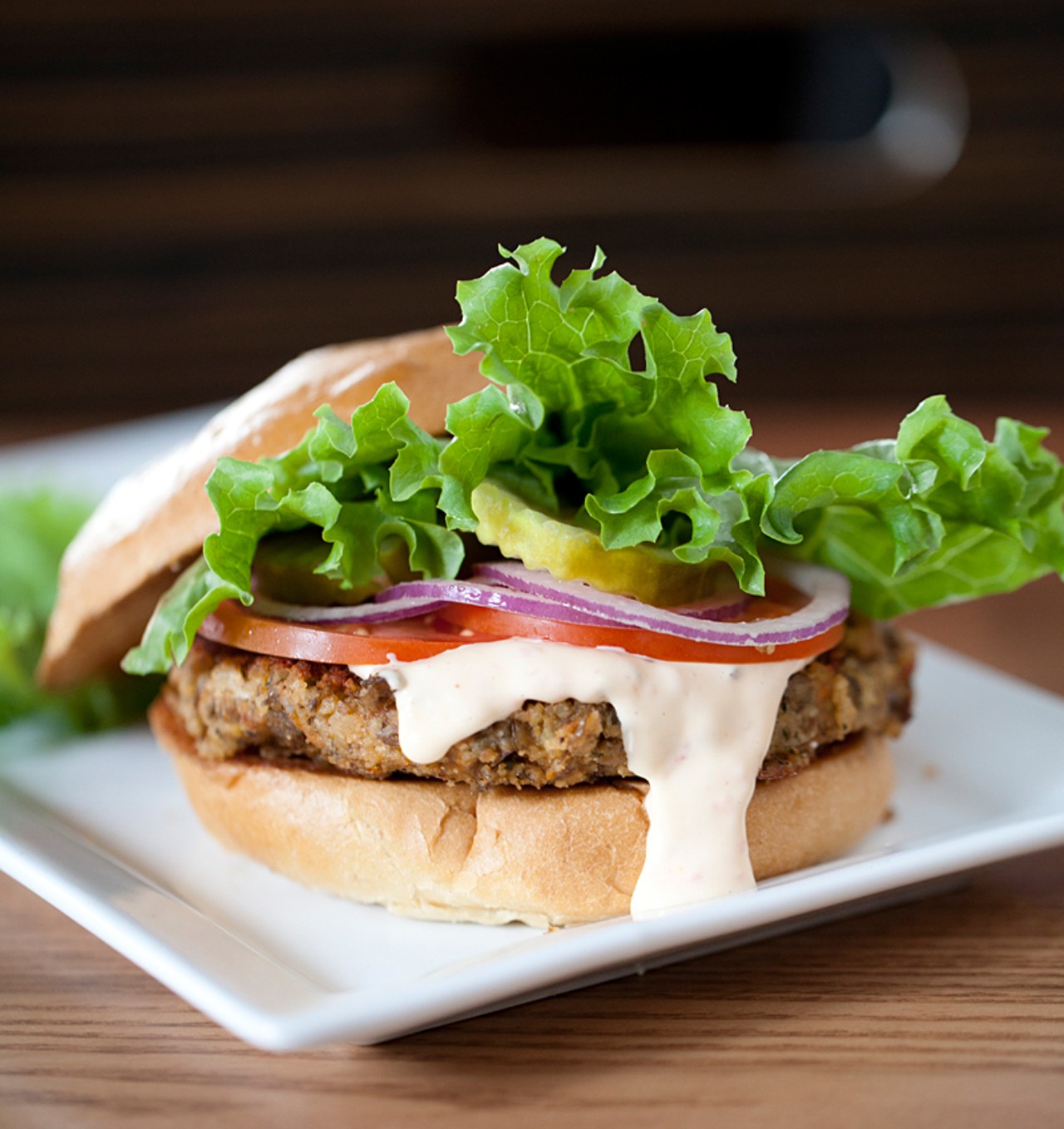 The veggie burger is prepared with lentils, vegetables and whole grains served with roasted red pepper mayonnaise, tomato, onion and lettuce.