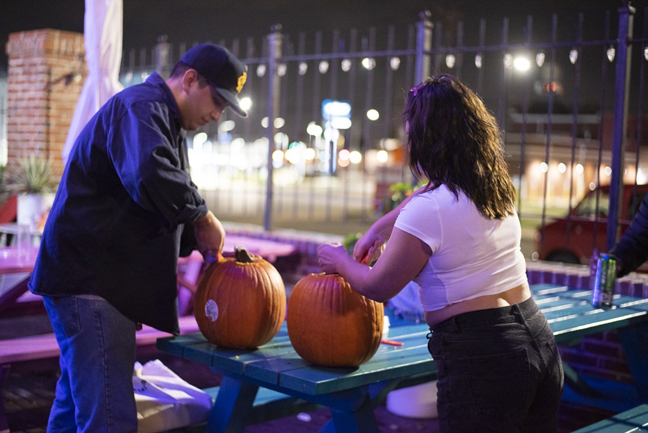 Two attendees carving their pumpkins.