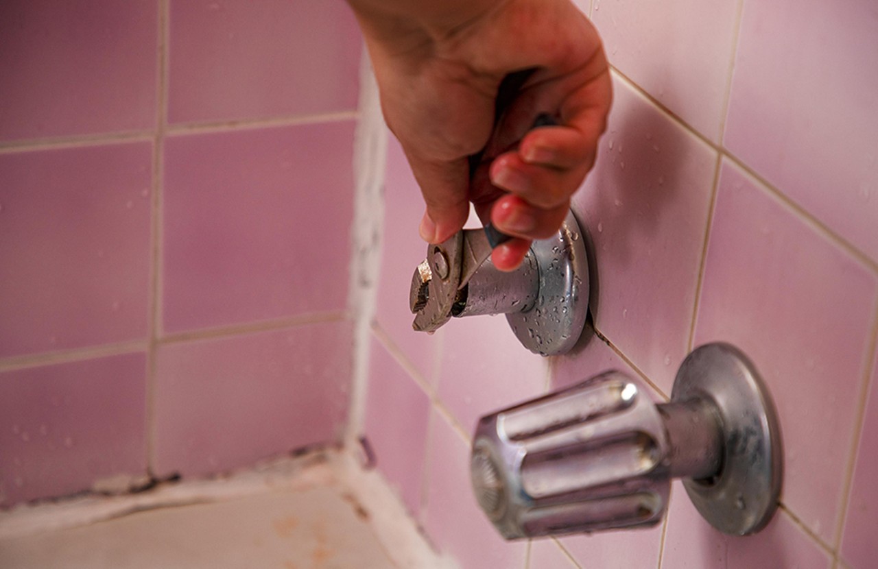 A resident who chose not to be identified demonstrates how she use a wrench to adjust her hot water for her shower.