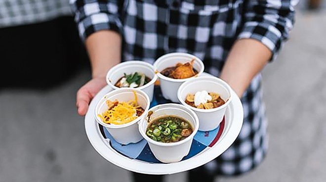 A woman holds a tray of chili samples.