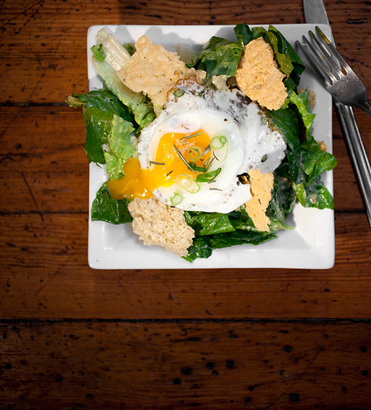 Caesar Salad is prepared with romaine, roasted parmesan, rosemary, farm egg and house dressing.