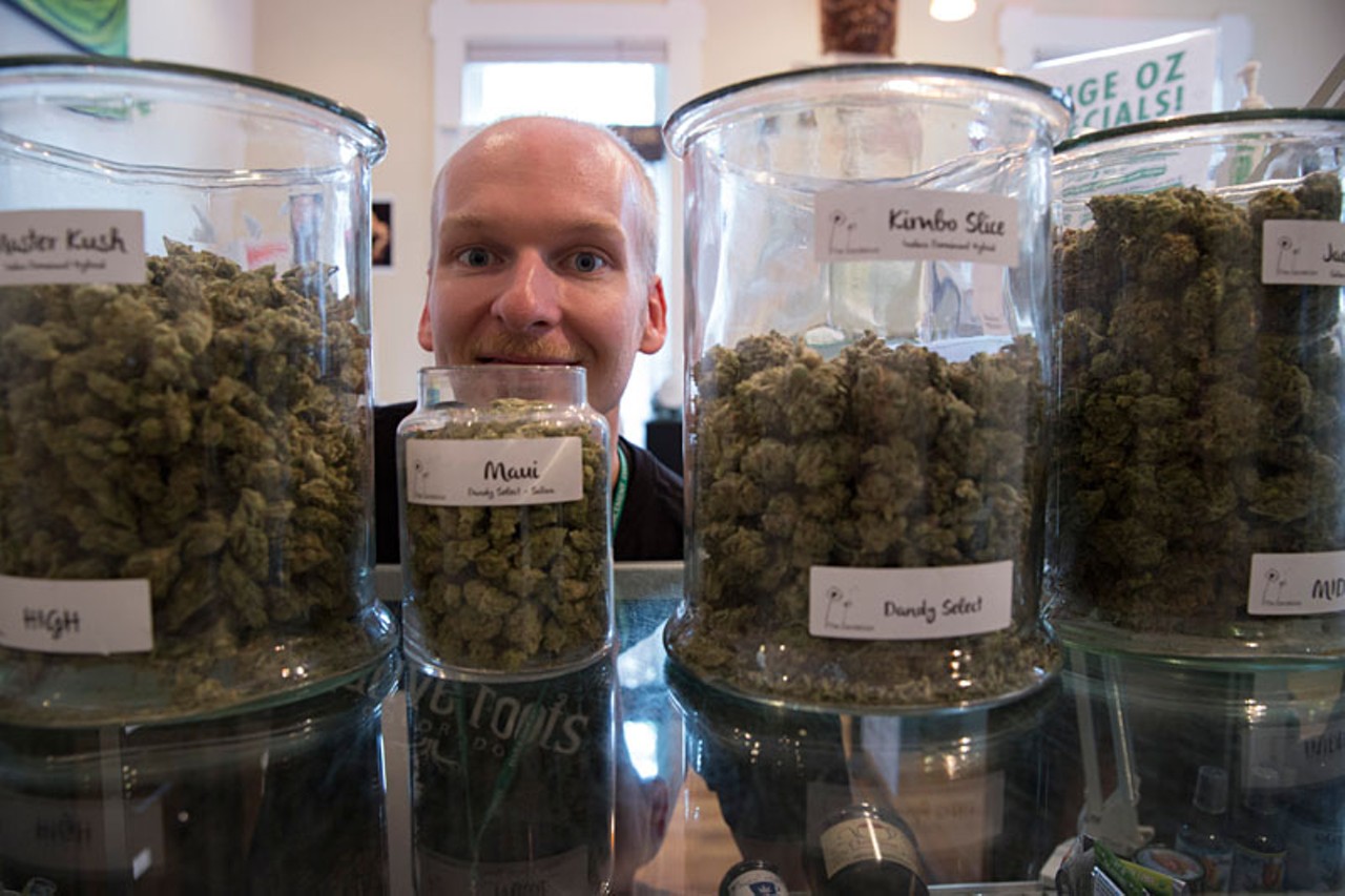 A budtender poses with jars of marijuana.