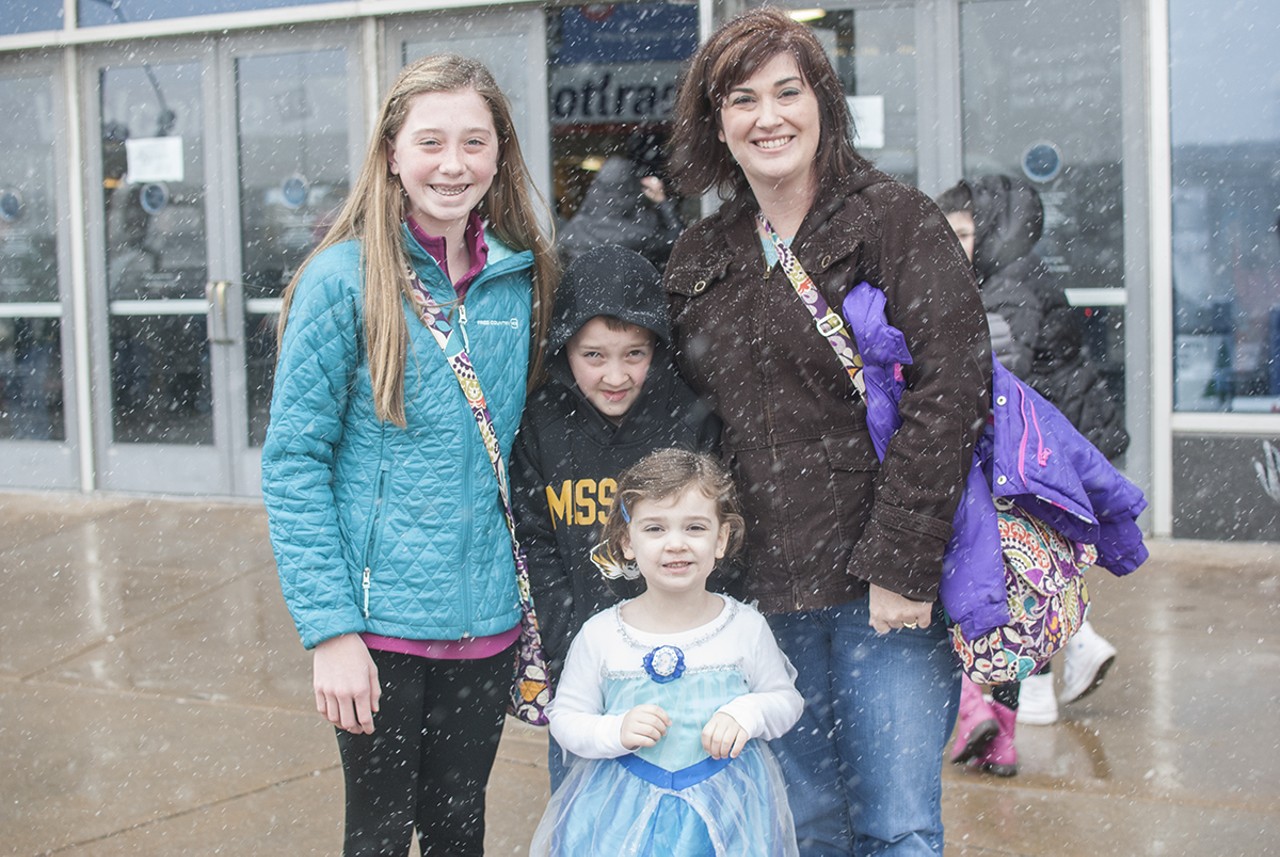 A family quickly poses for a picture with their youngest dressed in Frozen attire.