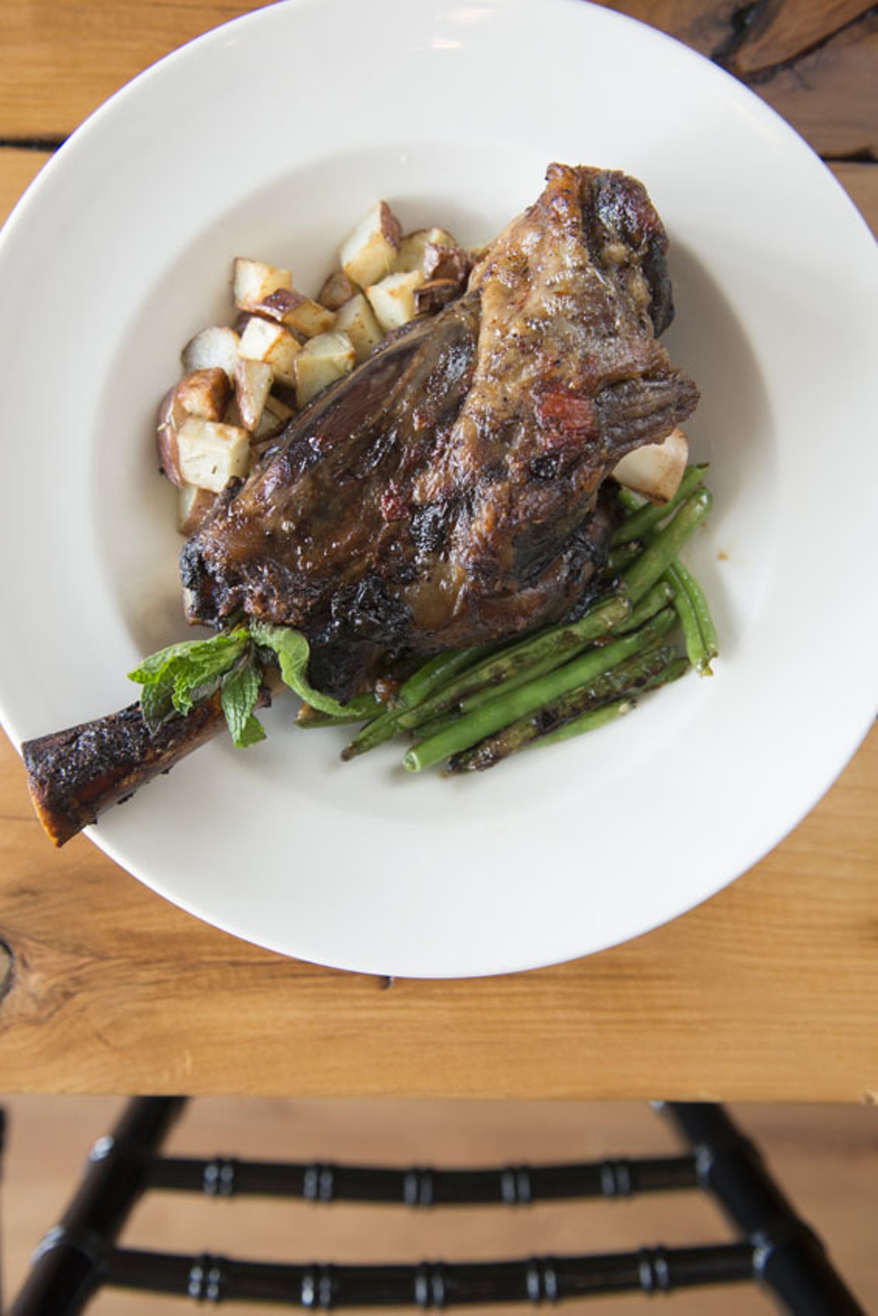 The lamb shank is slow roasted with tomatoes and basil, and it comes with vegetables.