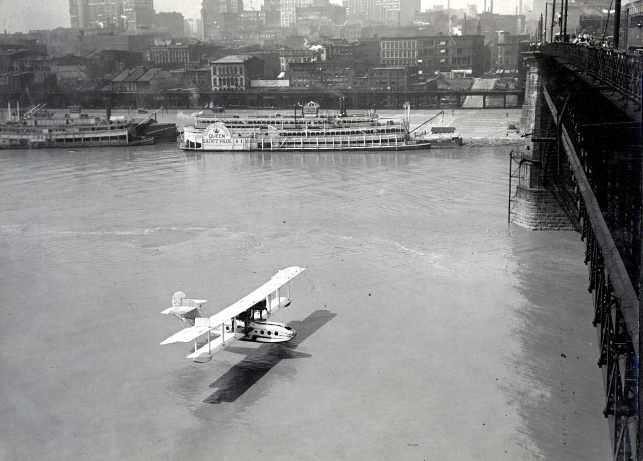 UNIDENTIFIED PILOT FLYING BENEATH THE EADS BRIDGE, 1920S
In 1910 the 'St. Louis Post-Dispatch' offered $2,500 to the first pilot daring enough to fly a plane through one of the Eads Bridge's arches. Thomas Baldwin was up to task and received cheers from crowds gathered on the levee when he threaded his plane into an opening less than 50 feet high on Sept. 10, 1910. Baldwin's stunt inspired riverfront daredevils for years to come, including this unidentified biplane pilot.
Bi-plane flying under the Eads Bridge. Photograph by Russell Froelich, ca. 1930s. Missouri Historical Society Collections.
