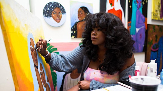 Woman paints a canvas.