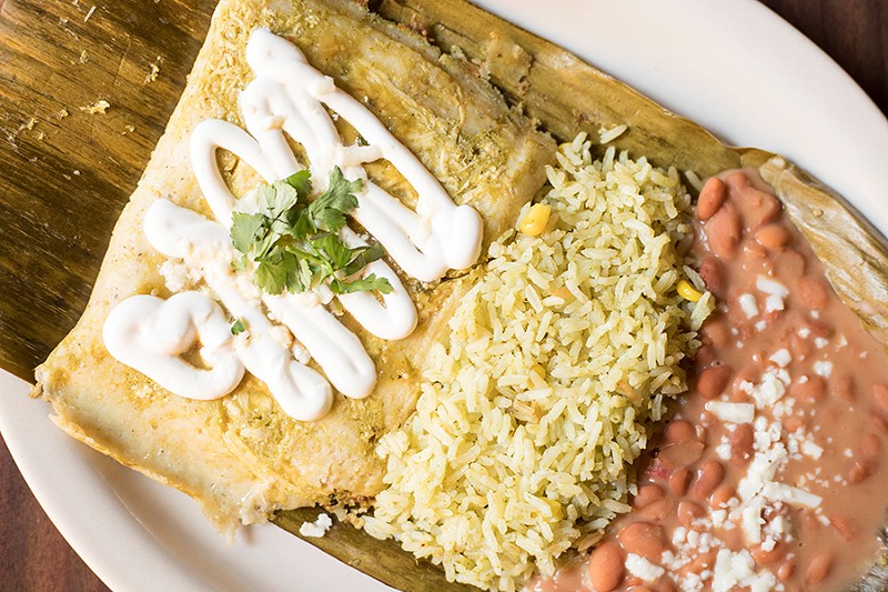 Chicken and salsa verde tamales are topped with sour cream and served with pinto beans and rice. - MABEL SUEN
