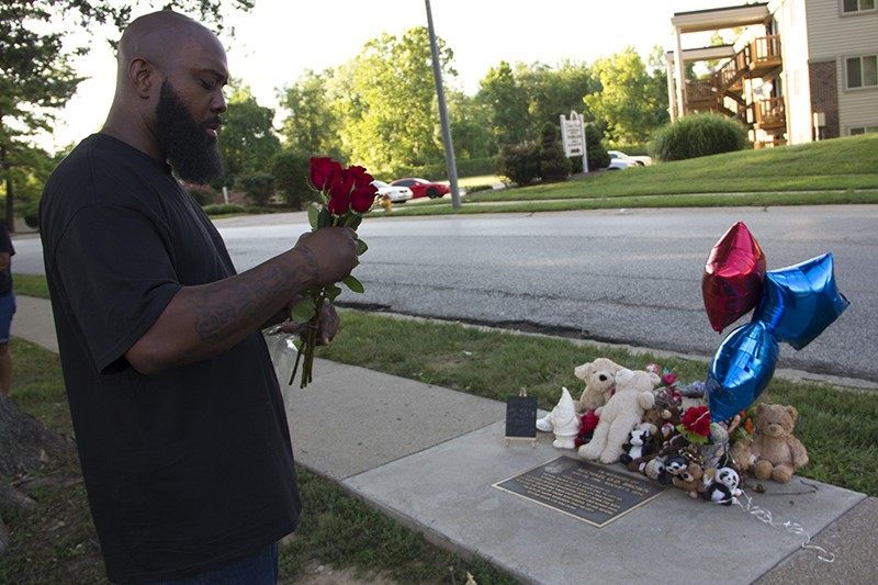 Michael Brown Sr. prepares to lay down a bouquet of roses at a memorial plaque for his son. - DANNY WICENTOWSKI