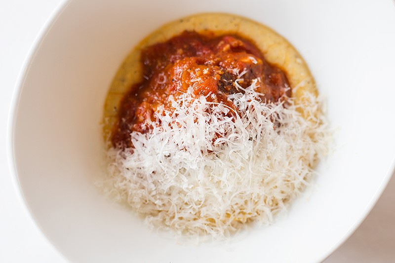 The meatball is served atop creamy polenta and parmigiano reggiano. - MABEL SUEN