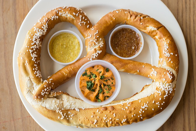 The giant pretzel comes with obatzda cheese, sweet mustard and onion mustard. - MABEL SUEN