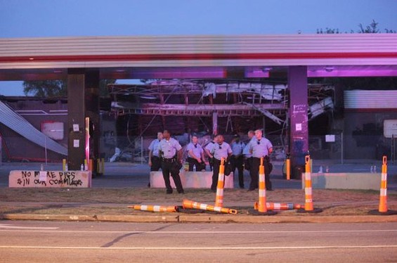 Police guard the burnt-out, graffitied QuikTrip in Ferguson. - Danny Wicentowski