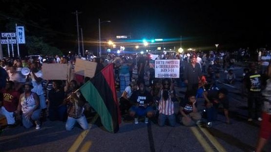 Protesters got on their knees in front of a police barricade on West Florissant Avenue. - Ray Downs