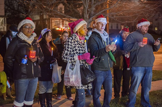 Maxine Harris (in pink) and other carolers sing outside of a Ferguson resident's home.