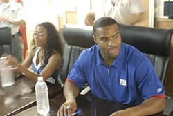 Umenyiora signing autographs on a USO tour. - Wikimedia Commons