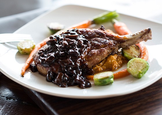 Deppe Farms' heritage-breed Duroc pork chop is served with Ozark Forest wild mushroom madeira sauce, Double Star Farms sweet potato and cauliflower mash, roasted baby carrots and Brussels sprouts. | Jennifer Silverberg