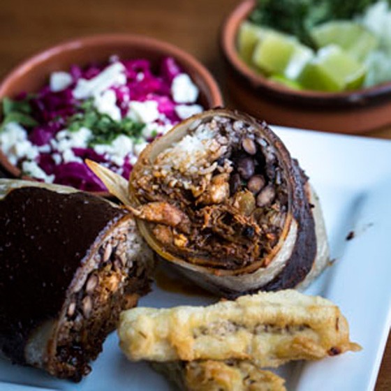 Mole poblano burrito, with slow cooked turkey in a blend of chile peppers, peanuts, mole, crema fresca, black beans and rice. | Jennifer Silverberg