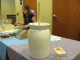 Two iconic symbols of Little House on the Prairie: A sunbonnet (worn by Pudd'nhead Books children's buyer Melissa Posten) and a butter churn.