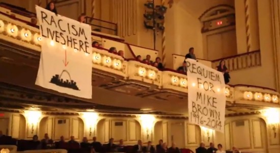 Protesters unfurl banners during the SLSO performance. - Screenshot from the video below.