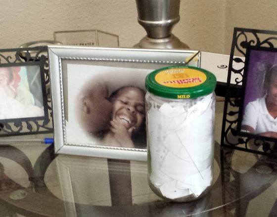 A jar full of Mike Brown's rap lyric ideas, written on tiny slips of paper, next to family photos at his grandmother's house. - Jessica Lussenhop