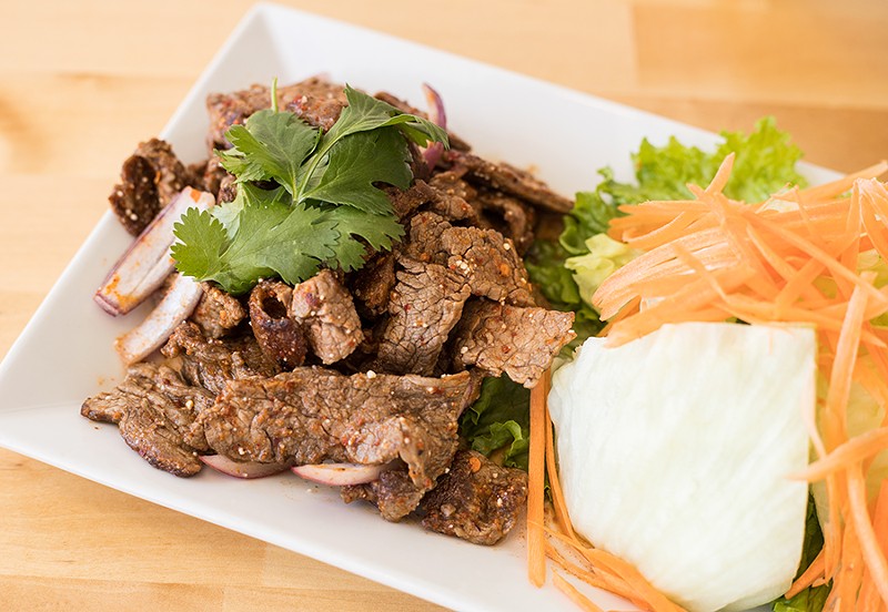 Nam Tok, or flame-grilled sliced beef, is tossed in a spicy lime dressing with toasted rice, red onions, green onions and cilantro. - MABEL SUEN