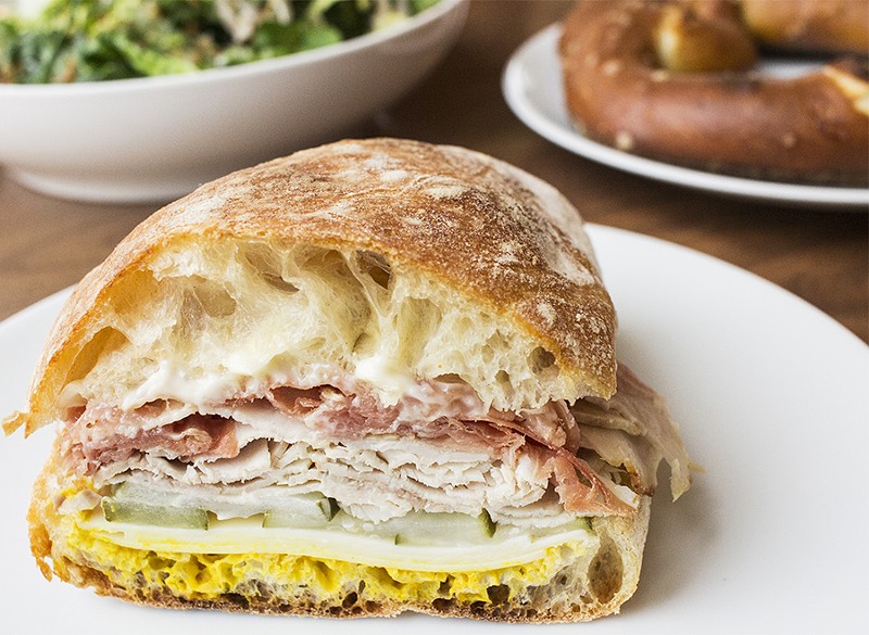 The roasted pork sandwich comes with country ham, gruyere, pickles, mustard and garlic mayonnaise on ciabatta. - MABEL SUEN