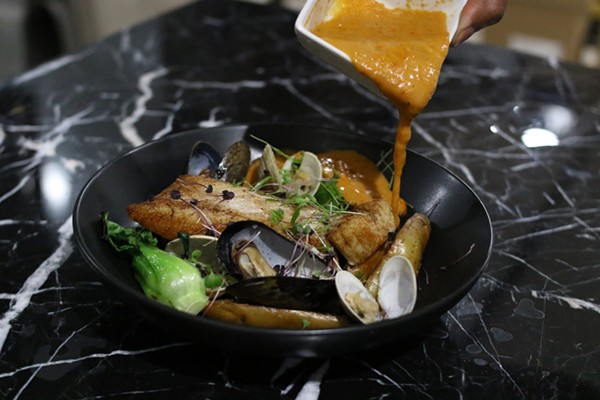 The sauce on the halibut is poured tableside, with littleneck clams, fingerling potatoes, baby bok choy and basil oil in a red curry. - Chelsea Neuling