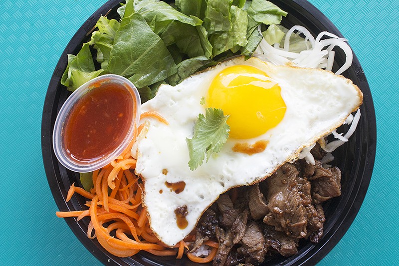 The boneless beef short rib rice bowl is served with with jasmine rice, romaine, sweet pickled carrots, pickled daikon, a fried egg and chili sauce. - PHOTO BY MABEL SUEN
