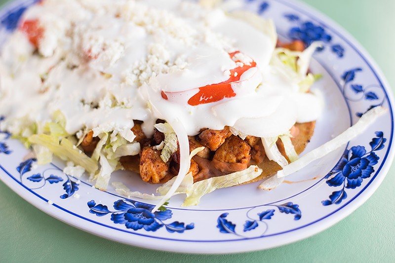 The sope’s masa basa soaks in the juices of its toppings — in this case, chicken with pinto beans, lettuce, tomatoes and sour cream. - MABEL SUEN