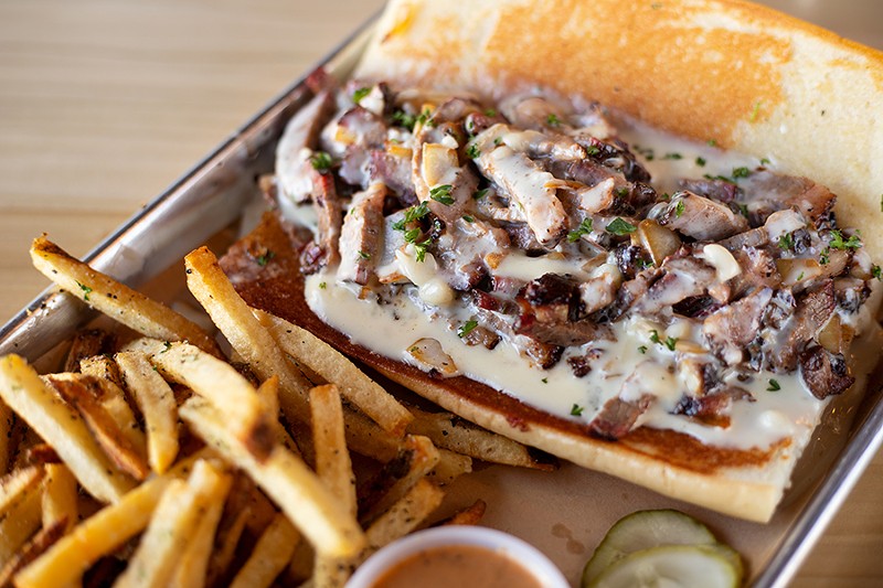 The #Beercheesesteak sandwich with brisket, charred onions and beer cheese served with fries. - MABEL SUEN