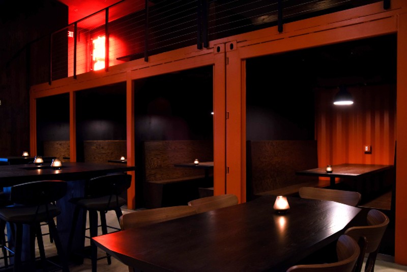 The ground-floor seating area features tables and six booths forged around shipping containers. - TRENTON ALMGREN-DAVIS