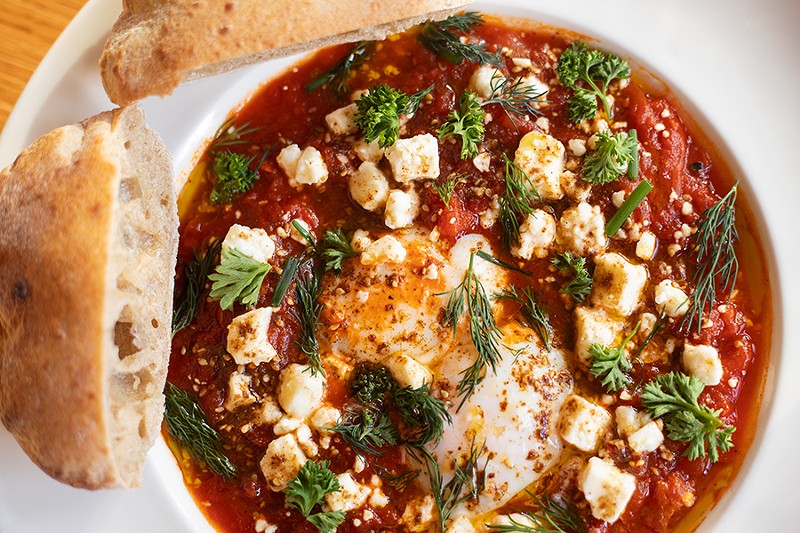 Shakshuka with spicy tomato and pepper stew, poached eggs, harissa, feta, herbs and sourdough pita. - MABEL SUEN