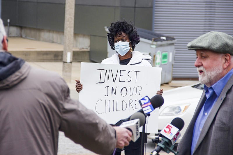 Gwendolyn Cogshell holds a sign urging school officials to "Invest in our children" during a teacher's union press conference opposing school closings on December 15. - DANNY WICENTOWSKI