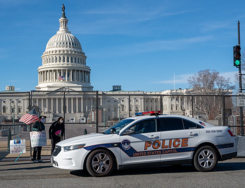 A couple stands by the Capitol with a tribute to Officer Brian Sicknick as a Capitol Police car drives up and inquires what they are doing. - VICTORIA PICKERING/FLICKR