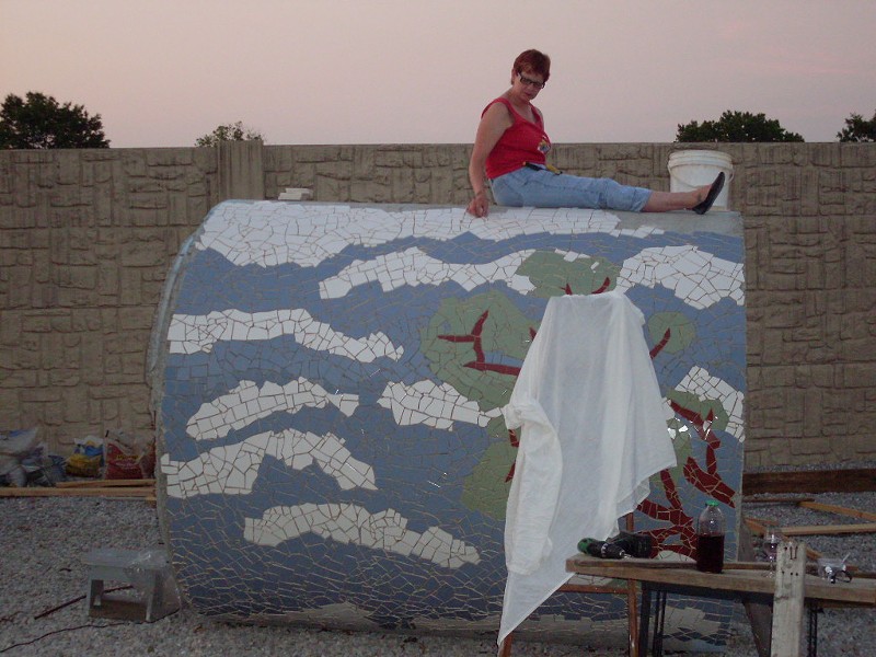 Jeanne Spezia, shown sitting atop the pipe as she covered its concrete surface with tiles. - JEANNE SPEZIA