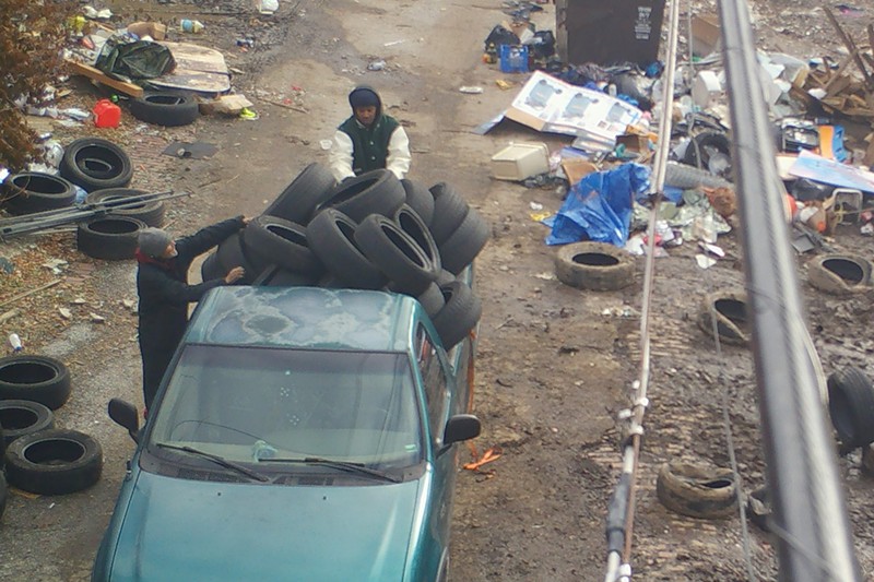 Caught on police camera in February, a two-person team of trash dumpers unloads tires into an alley. - SLMPD