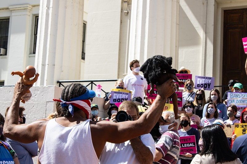 A counter-protestor raises two baby dolls and yells at the crowd that has gathered to support reproductive freedom. - JENNA JONES