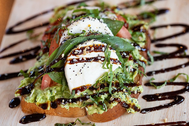 Caprese avocado toast on multigrain bread with avocado spread, heirloom tomato, buffalo mozzarella and fresh basil topped with an over-medium, local free-range egg and drizzled with balsamic reduction. - MABEL SUEN