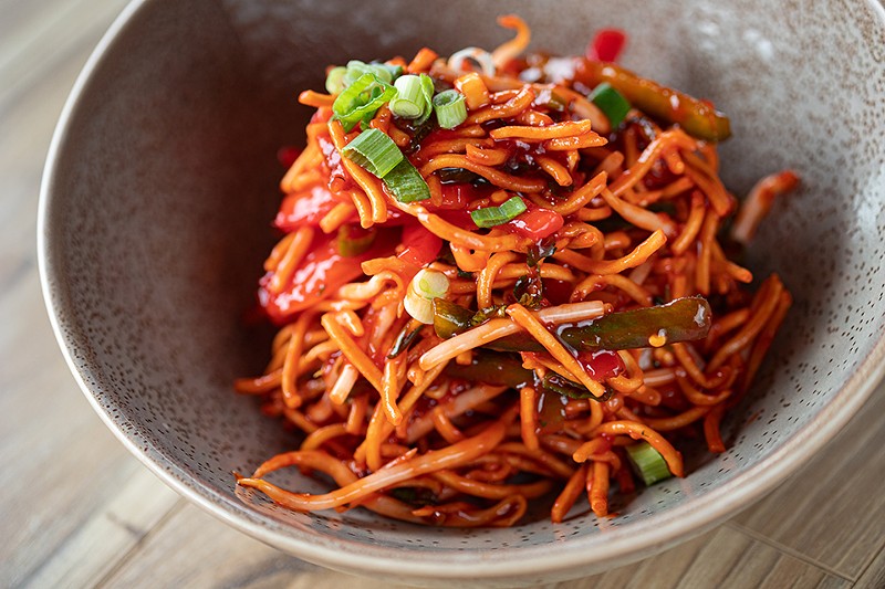 The crispy noodle salad features bell peppers, onions and a vibrant sweet and spicy behl sauce. - Mabel Suen