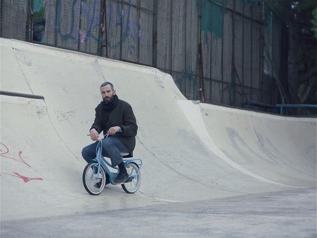 Aris attempts to recapture his memory by completing a series of human milestones, including riding a child's tiny two-speed at a skate park, and documenting them with a Polaroid camera. - Courtesy Dirty Films