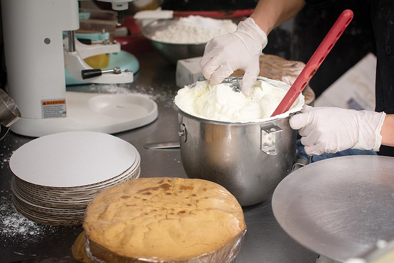 A baker dips into a pot of frosting
