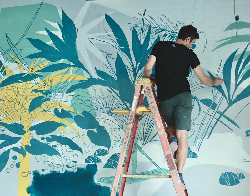 Noah MacMillan working on a mural.