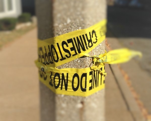 Yellow caution tape warning of a crime scene is wrapped around a pole.