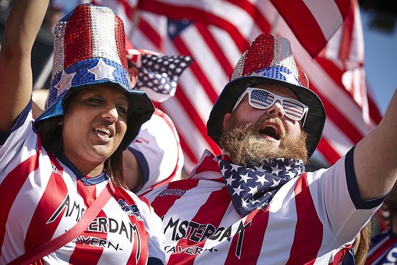 Two fans cheer decked in red-and-wide America-styled hats, sunglasses and t-shirts.