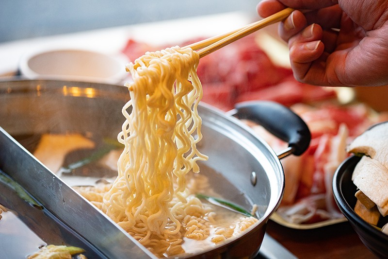Noodles dipped into a hot pot.